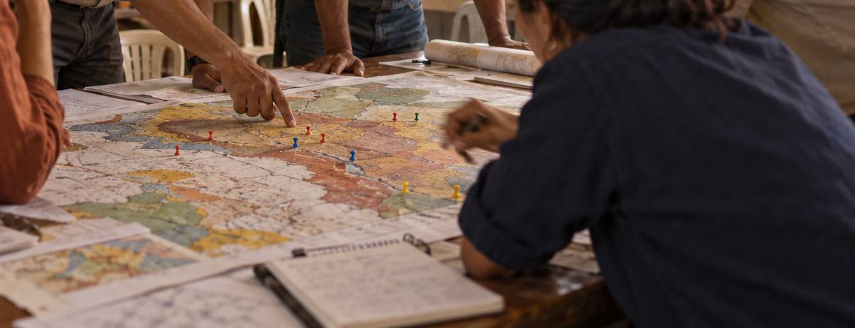 Manos señalando un mapa geológico sobre una mesa durante una sesión de formación